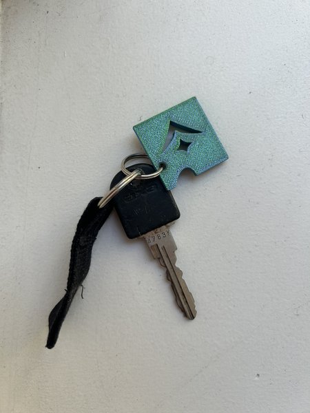 Bicycle key Fietssleutel (1) met vierkante groenige hanger en zwart stukje veter