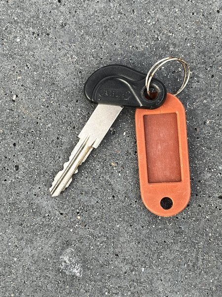 Key Zwarte sleutel met donker oranje naambordje zonder gegevens.