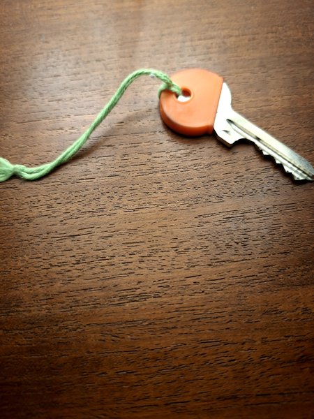 Key Zilverkleurig met rood hoesje en groen touwtje
